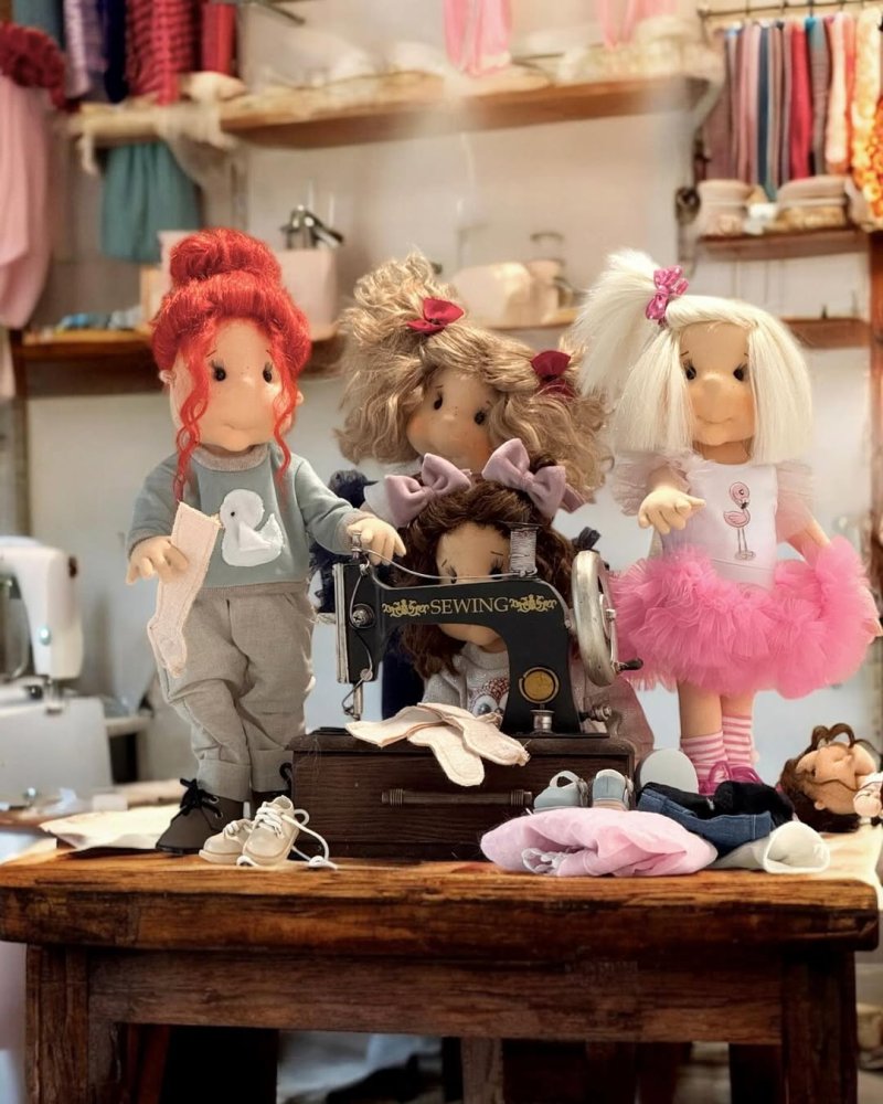 Ručne šitá bábika Lulludolls sediaca medzi doplnkami a oblečením